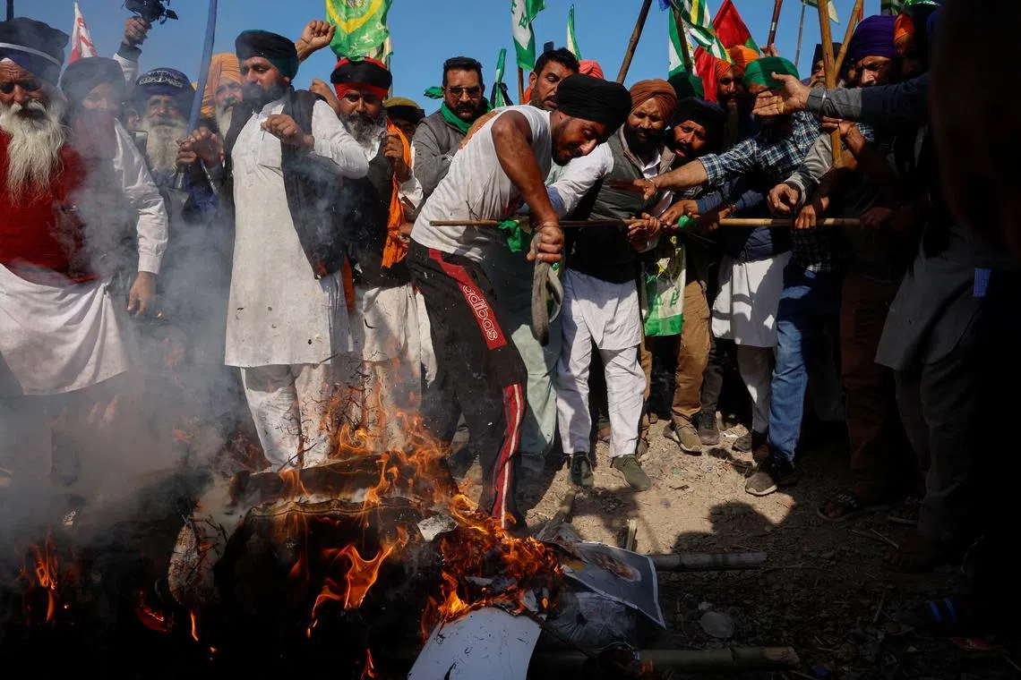 Farmers shout slogans as they burn an effigy of Prime Minister Narendra Modi and other ministers at a protest site, during the march towards New Delhi to push for better crop prices promised to them in 2021.