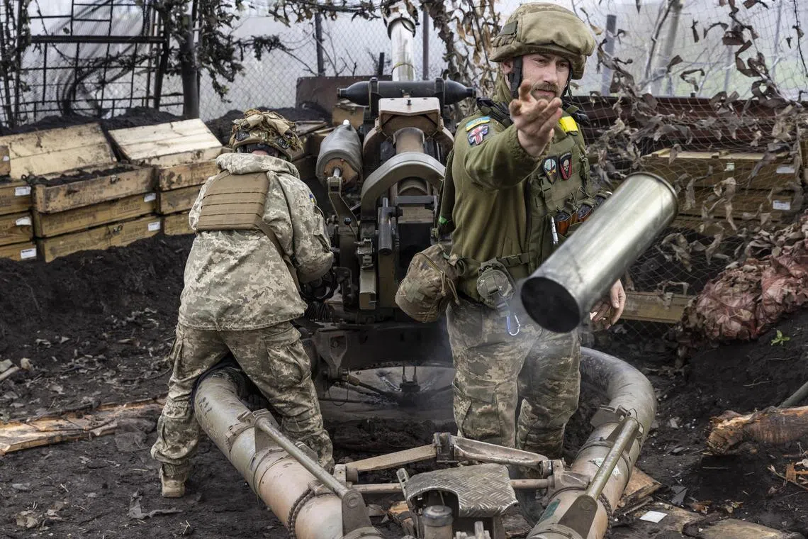 A soldier tosses aside a smoking, spent shell as a Ukrainian artillery unit fires its mobile howitzer at a Russian position, in Ukraine's Zaporizhzhia region.