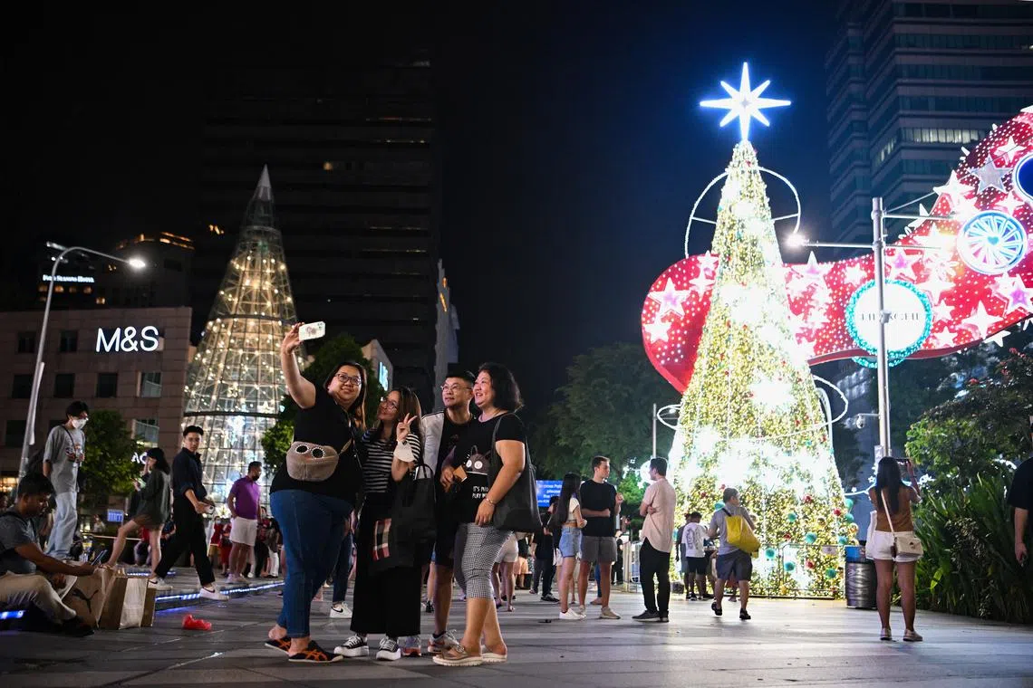 ST20221112-202264349733-Lim Yaohui-pixlightup13/ People pose for photographs with a giant Christmas tree with Christmas lights outside ION Orchard along Orchard Road on Nov 12, 2022. (ST PHOTO: LIM YAOHUI)