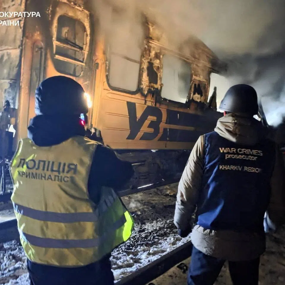 A war crimes prosecutor and a police officer working at the scene of a Russian drone attack on a passenger train in Ukraine's Kharkiv region on Jan 27.