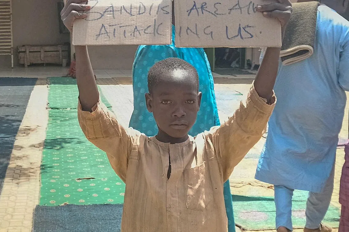 FILE PHOTO: A boy holds a sign to protest against, what a teacher, local councilor and parents said, the kidnapping of hundreds school pupils by gunmen after the Friday prayer in Kaduna, Nigeria March 8, 2024. REUTERS/Stringer/File Photo
