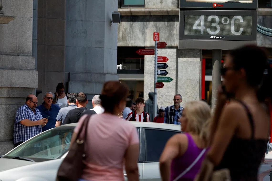FILE PHOTO: People walk near a sign indicating 43 degrees Celsius (109 F) as near record temperatures continue to affect the country, in Bilbao, Spain June 17, 2022. REUTERS/Vincent West/File Photo