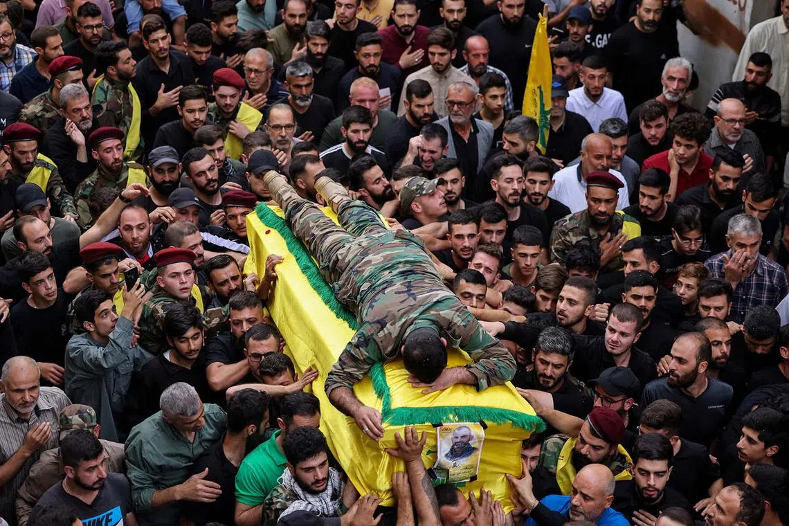 Nazih, son of Hezbollah member, Mounir Youssef Achour, who was killed in southern Lebanon amidst tension between Israel and Hezbollah, lies on top of his father's coffin as he mourns him during his funeral, in Chaqra, Lebanon, Oct 30.