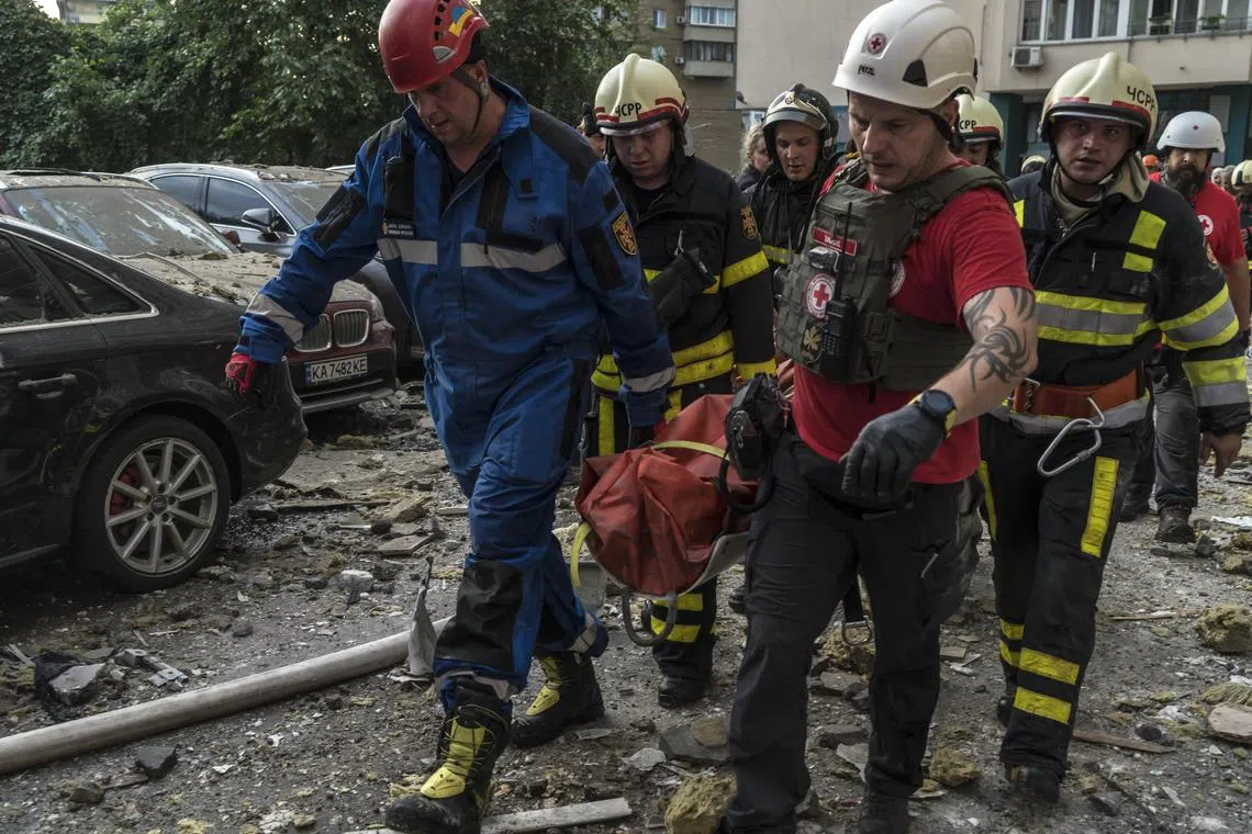 Rescue workers carry a wounded woman from a high-rise residential building in Kyiv, after it was hit by a Russian missile.