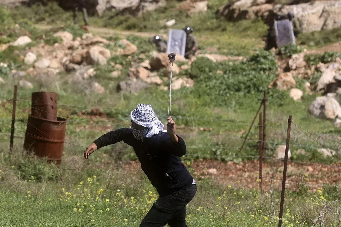 A Palestinian protester uses a slingshot to hurl a stone towards Israeli soldiers during clashes.