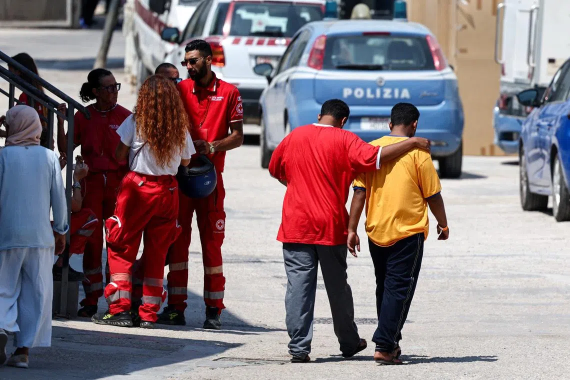 Members of the Italian Red Cross speak to each other outside the hotspot, a reception centre for migrants, in Lampedusa, Italy, on Aug 15, 2025.
