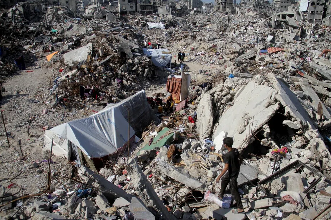 Palestinians walk past the rubble of houses and buildings destroyed during the Israeli offensive, amid a ceasefire between Israel and Hamas, in Jabalia refugee camp in the northern Gaza Strip January 29, 2025. REUTERS/Mahmoud Issa