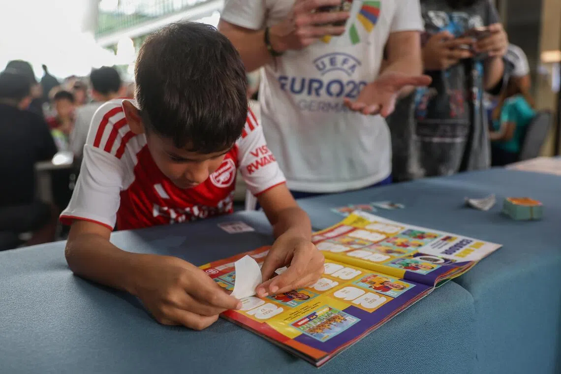 Nine-year-old Vincent Bett, a Primary 3 pupil at Nanyang Primary School, pasting a Panini sticker into his family’s shared album.