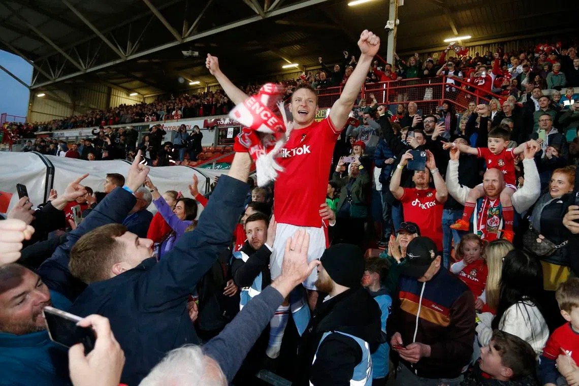 Soccer Football - National League - Wrexham v Boreham Wood - Racecourse Ground, Wrexham, Britain - April 22, 2023 Wrexham's Paul Mullin celebrates with fans after the match as Wrexham win the National League and promotion to League Two Action Images via Reuters/Ed Sykes