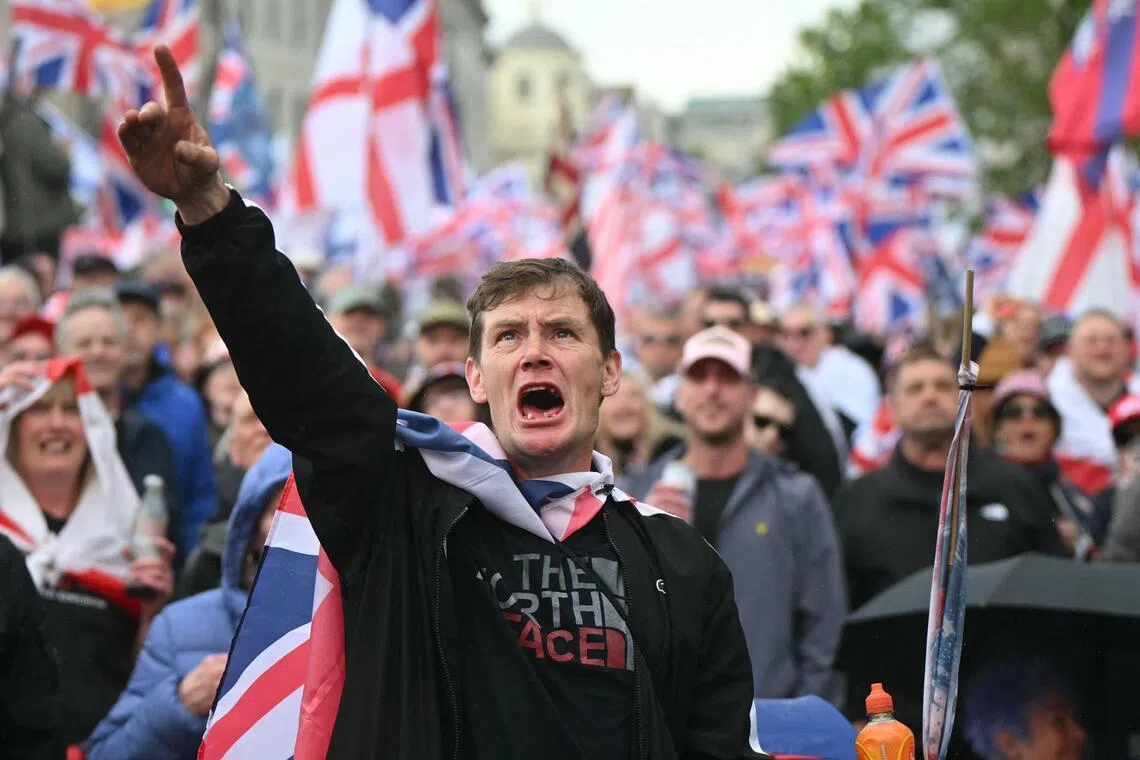 Supporters of British far-right activist Tommy Robinson watch the speeches on screens after taking part in a march organised by Unite The Kingdom, in central London on May 16.