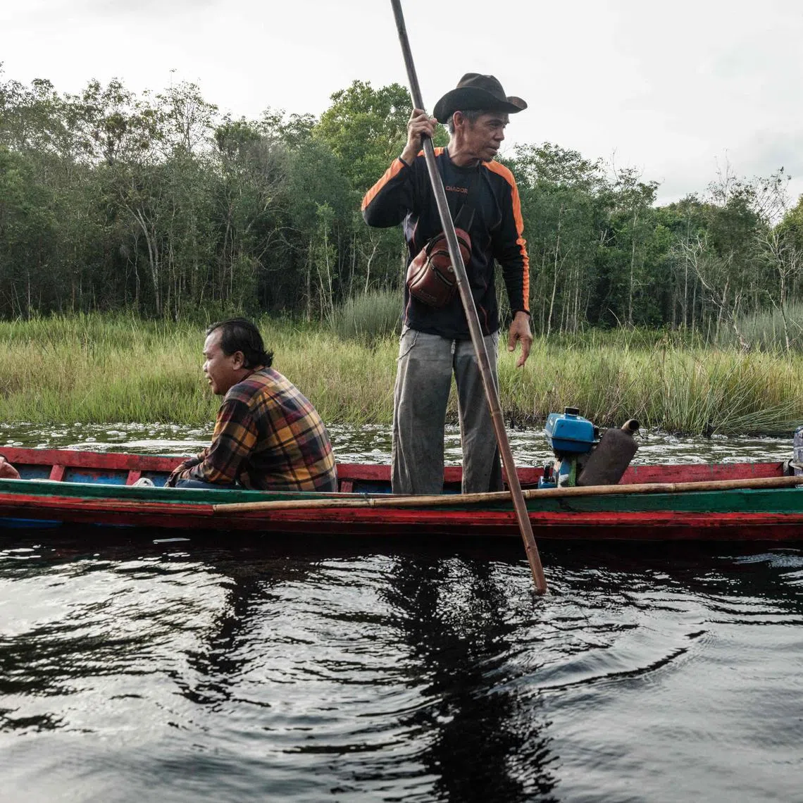 A man poles a boat along a local canal built to navigate through the peatland forest in Lebung Itam, South Sumatra, on June 11, 2025.