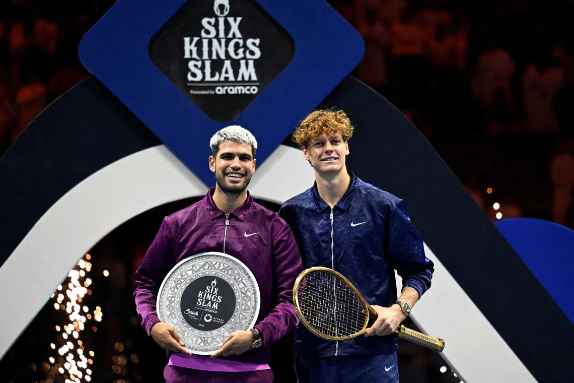 Tennis - Six Kings Slam - ANB Arena, Riyadh, Saudi Arabia - October 18, 2025 Italy's Jannik Sinner celebrates with a racket after winning the final as Spain's Carlos Alcaraz poses with the runners up trophy REUTERS/Stringer
