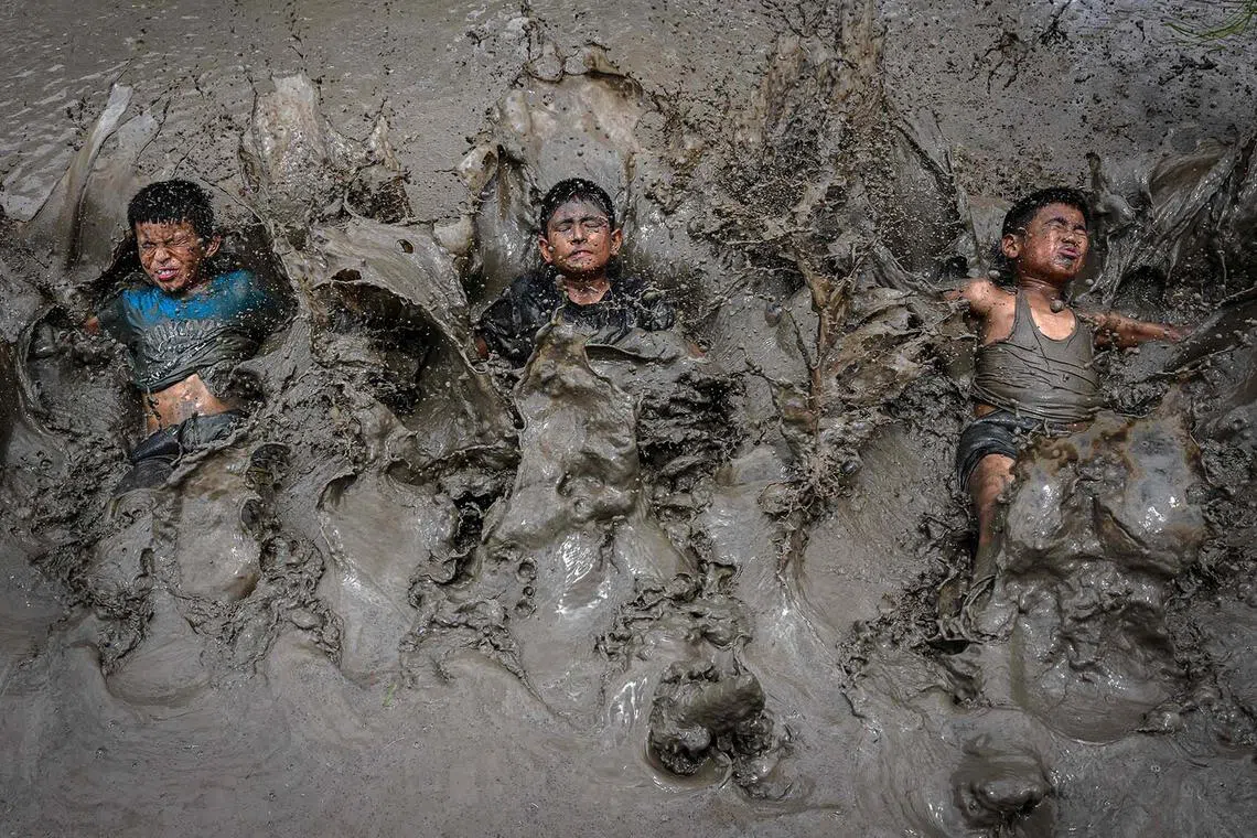 Children splashing mud as they celebrate National Paddy Day, which marks the start of the annual rice planting season, at a paddy field in Jeetpur Phedi village on the outskirts of Kathmandu on June 29, 2025. 