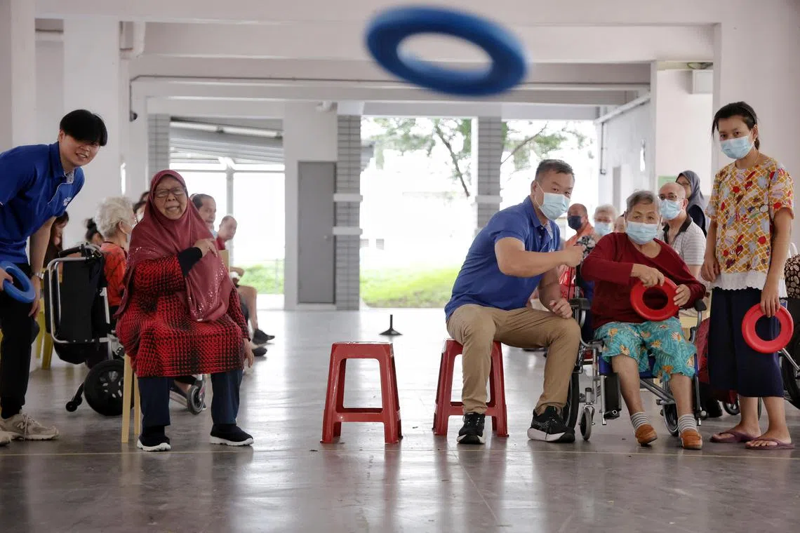 Mdm Sakyah Binte Sapari (seated left, in red), 74, participating in an adapted version of disc golf at the void deck of Block 212 Pasir Ris Street 21 on Jan 23, 2024. Story on some adaptive sports that active ageing centres offer to keep seniors active.