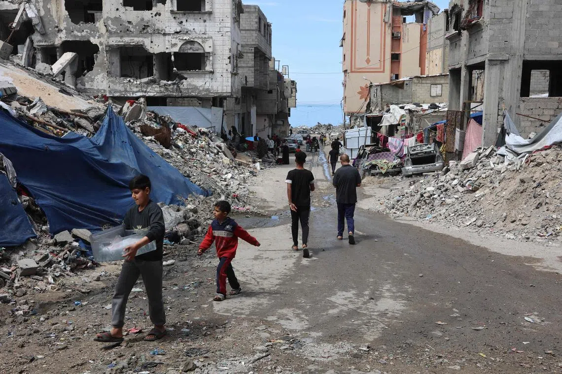 Palestinians walking past the debris of buildings in Gaza City on March 28.