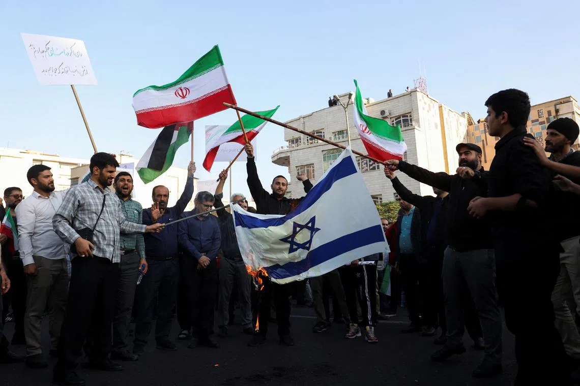 Protesters burn the Israeli flag during an anti-Israel protest in Teheran, Iran, on Oct 18. Iran said it used ballistic missiles to hit Israeli "espionage centres".
