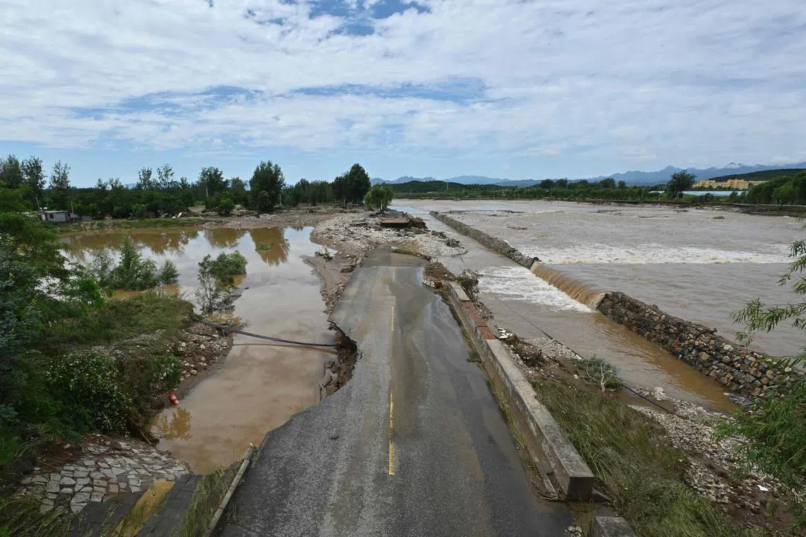 A flood-damaged road is seen alongside a swollen river following heavy rains in Miyun district, on the outskirts of Beijing, on July 29. 