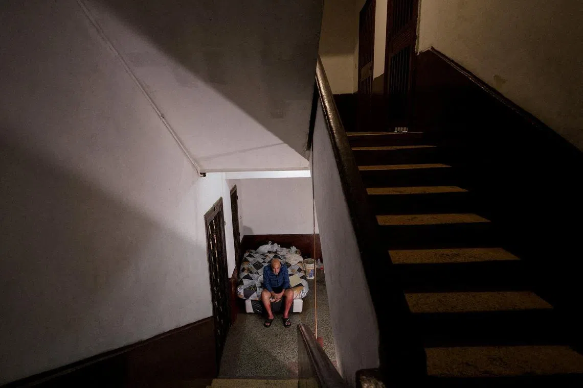 A Venezuelan-Uruguayan prisoner granted house arrest after two years in Tocuyito prison, sitting on a mattress outside his home after finding that a police officer from the unit that arrested him had taken over his apartment, leaving him with nowhere to sleep or serve his sentence, in Caracas, Venezuela, on May 26, 2026. 