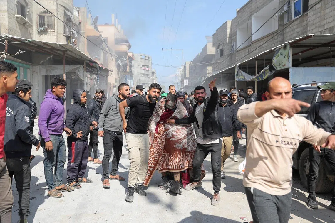 Palestinians help an injured man, at the site of an Israeli strike on a house in Rafah, in the southern Gaza Strip.    