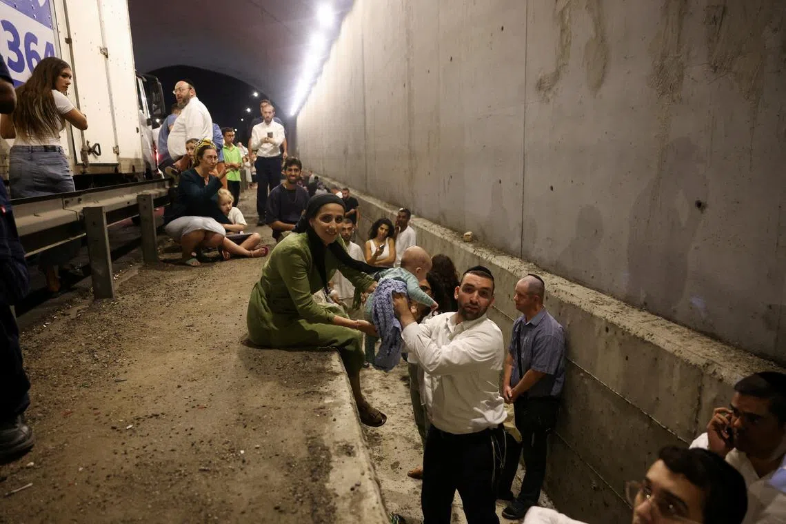 People take shelter during an air raid siren after Iran fired a salvo of ballistic missiles, in central Israel, on Oct 1.