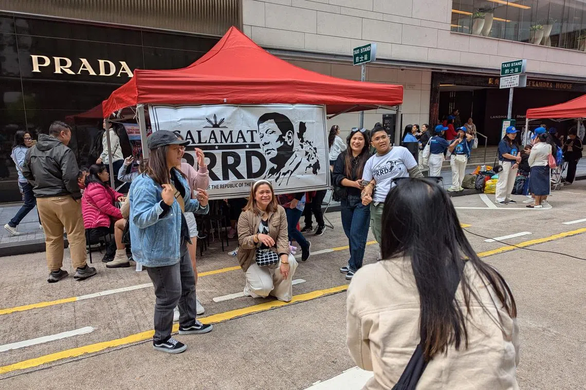 Filipino migrant workers pose for a photo next to a banner expressing thanks to former Philippine president Rodrigo Duterte in the Central district in Hong Kong, on March 16.
