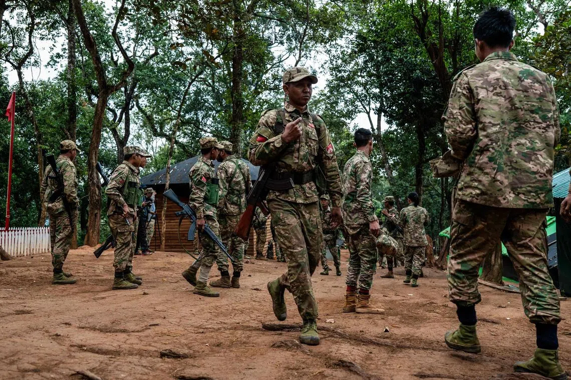 This photo taken on December 8, 2023 shows members of the Mandalay People’s Defense Forces (MDY-PDF) walking after a flag raising ceremony at their base camp in the forest near Namhsan Township in Myanmar’s northern Shan State. A squad of Myanmar pro-democracy fighters works quickly to ready drones for an attack on a nearby military base, the latest target in a wave of aerial assaults that has helped turn the war against the junta. (Photo by AFP) / TO GO WITH Myanmar-coup, FOCUS