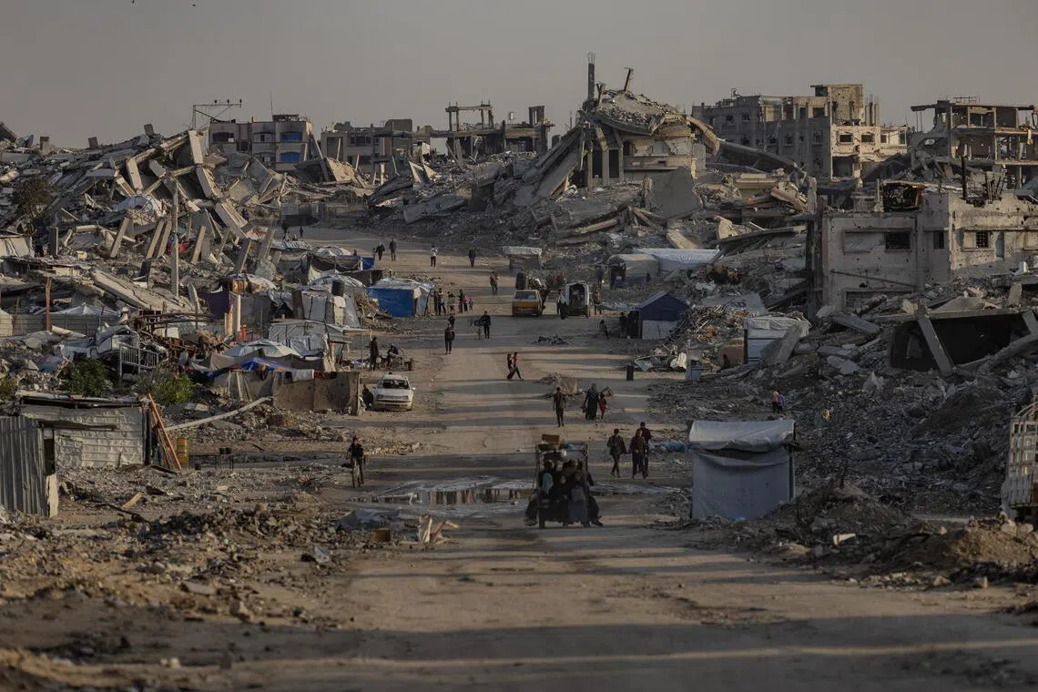 People walk between destroyed buildings in the Jabalia camp near Gaza City, on Nov 18, 2025.