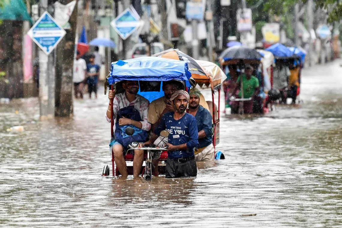 Residents commute in cycle rickshaws through a flooded street after heavy rains in Guwahati, in India's Assam state on May 31, 2025. Torrential monsoon rains in India's northeast triggered landslides and floods that swept away and killed at least five people in Assam, disaster officials said on May 31. (Photo by Biju BORO / AFP)