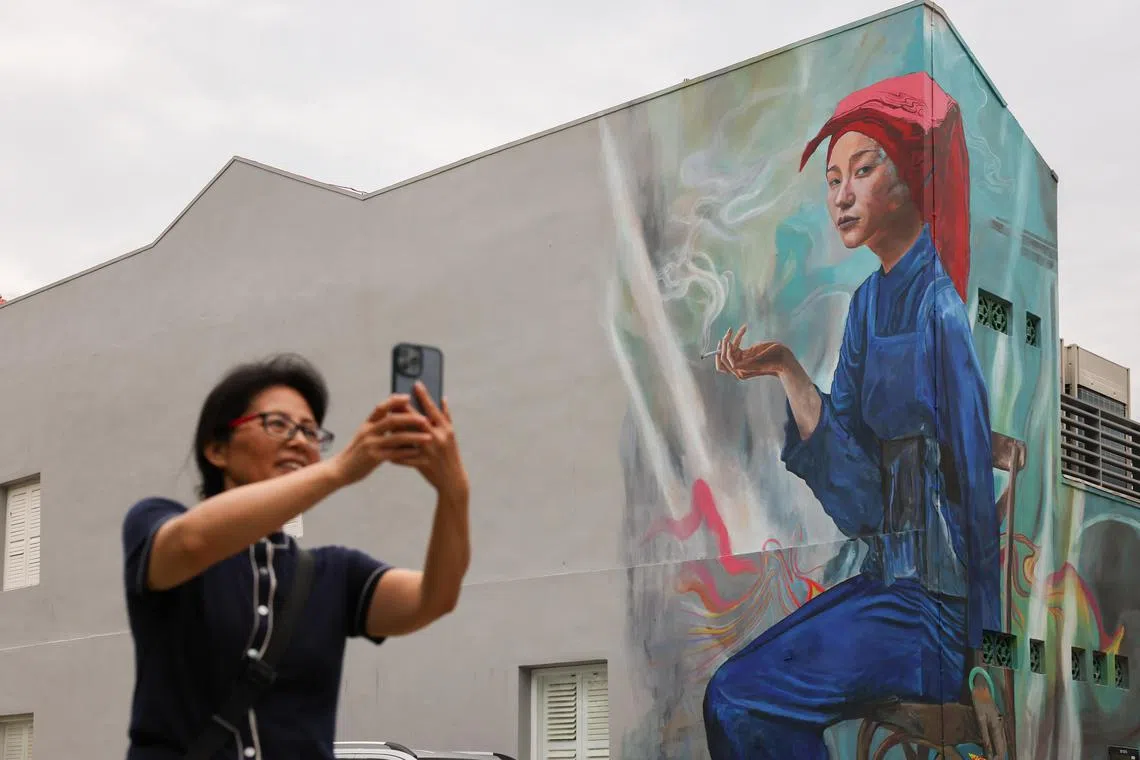 ST20240621_202498474034/pixmural21/Brian Teo/Passers-by taking pictures of Sean Dunston's mural of a young Samsui woman holding a smoking cigarette at 297 South Bridge Road on June 21, 2024. ST PHOTO: BRIAN TEO