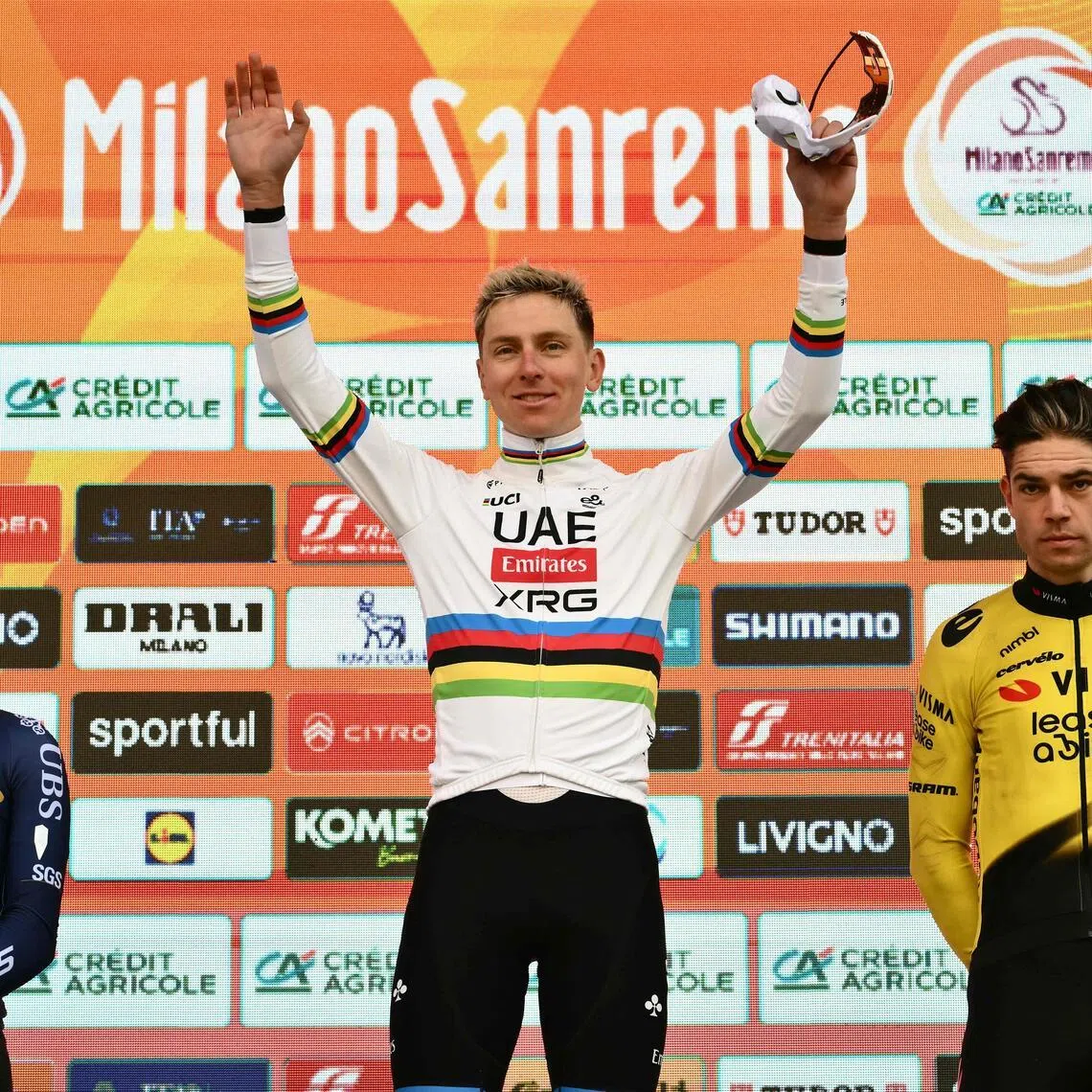 Slovenian rider Tadej Pogacar celebrating on the podium of the 117th Milan-San Remo one-day classic cycling race, with second-placed Briton Thomas Pidcock (left) and third-placed Belgian Wout van Aert on March 21, 2026.