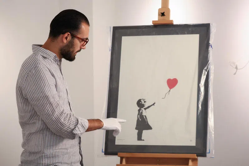 Gallery manager Lindor Mehmetaj with the print of Banksy's "Girl with Balloon", after it was returned to the London gallery.