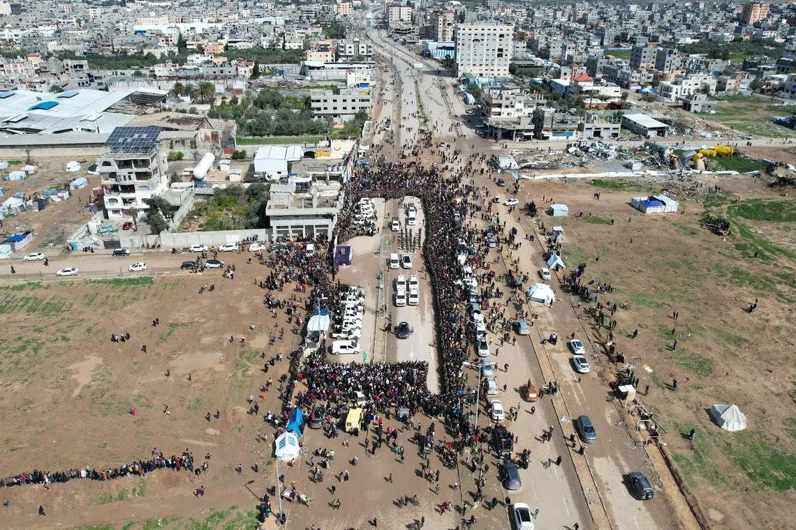 A drone view shows Palestinians and Hamas militants gathering around Red Cross vehicles on the day of the release of Eliya Cohen, Omer Shem Tov, and Omer Wenkert, hostages held in Gaza since the deadly October 7, 2023 attack, as part of a ceasefire and a hostages-prisoners swap deal between Hamas and Israel, in Nuseirat, central Gaza Strip, February 22, 2025. REUTERS/Stringer