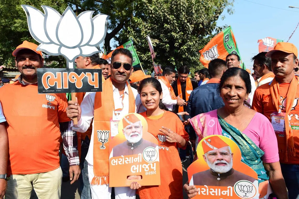 Bhartiya Janta Party (BJP) supporters hold placards with pictures of Indian Prime Minister Narendra Modi during a roadshow in Ahmedabad on Nov 30, 2022. 