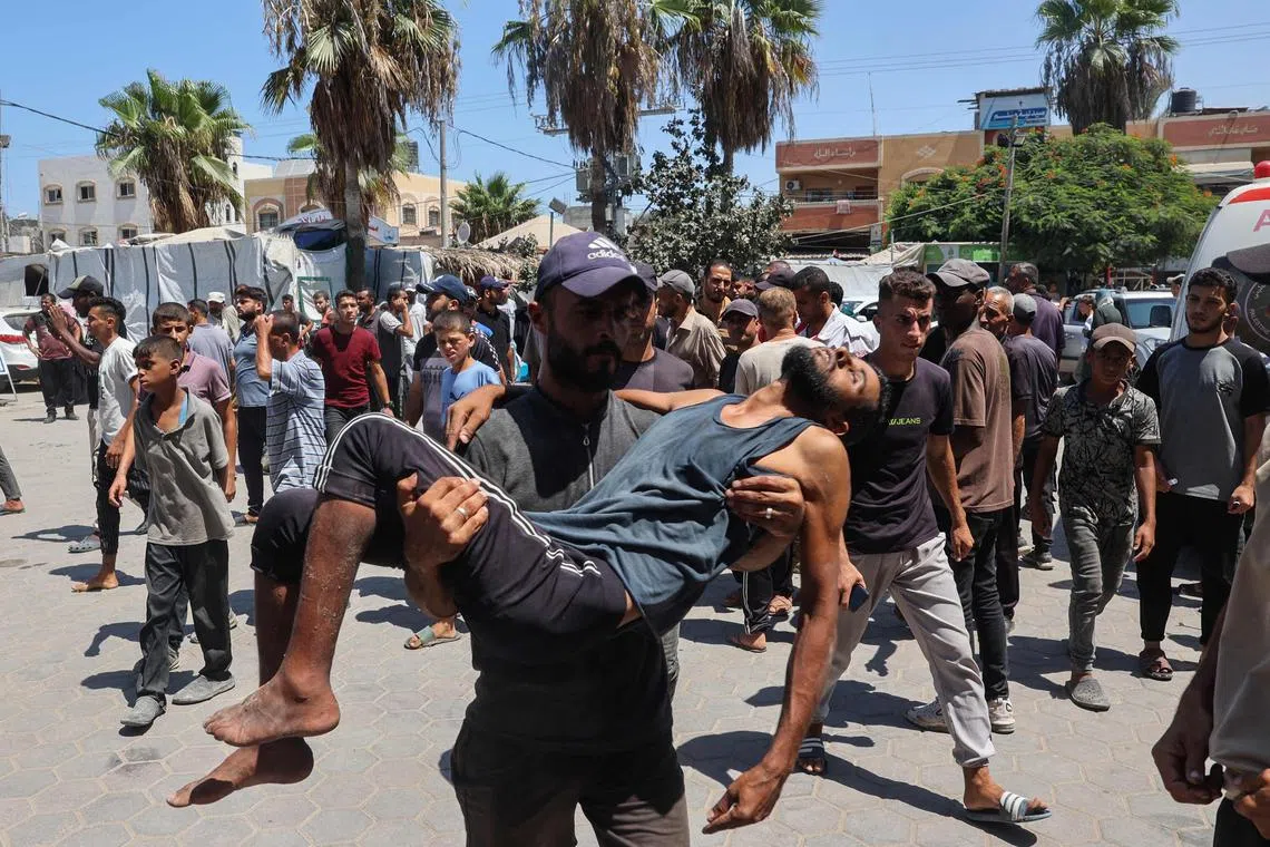 A Palestinian carries a man injured in an Israeli air strike in Deir Al-Balah on Aug 13 that killed at least six people.