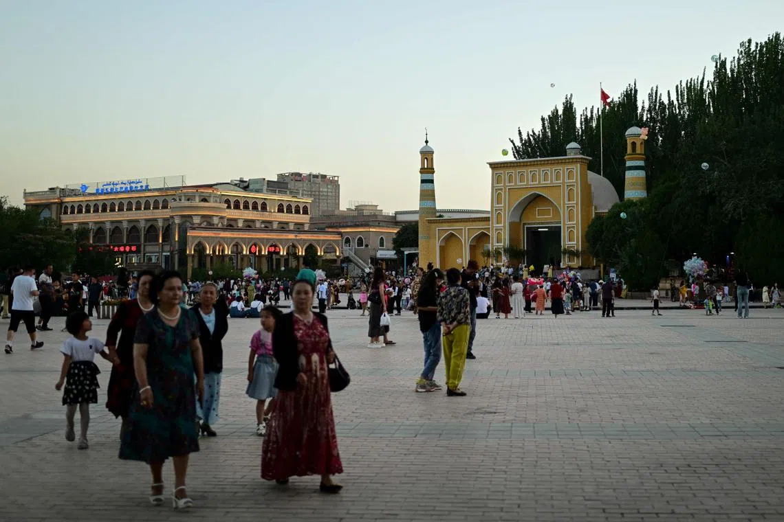 This picture taken on July 13, 2023, shows Uyghur people outside the Id Kah Mosque in Kashgar city in northwestern China's Xinjiang region. (Photo by Pedro PARDO / AFP)