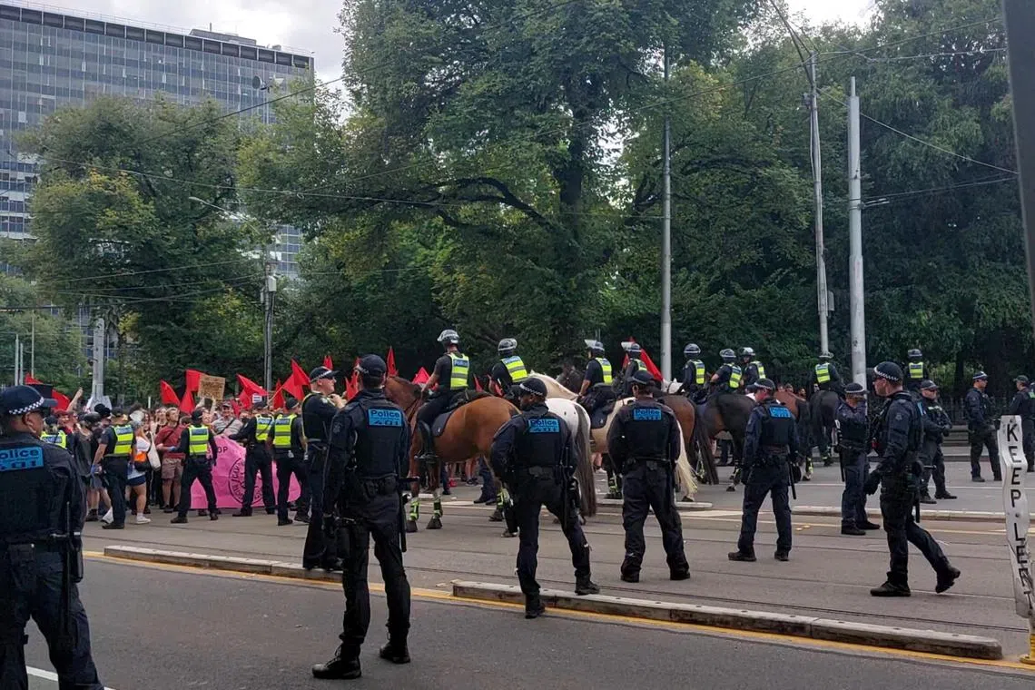 Police officers stand between transgender rights protesters and anti-transgender rights protesters at a protest in Melbourne on March 18, 2023.