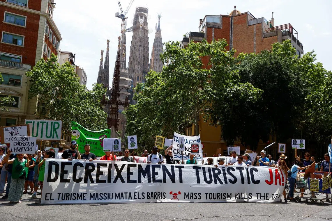 People hold a banner which reads \"Decrease tourism now\" during a protest against mass tourism, in Barcelona, Spain June 15, 2025. REUTERS/Bruna Casas
