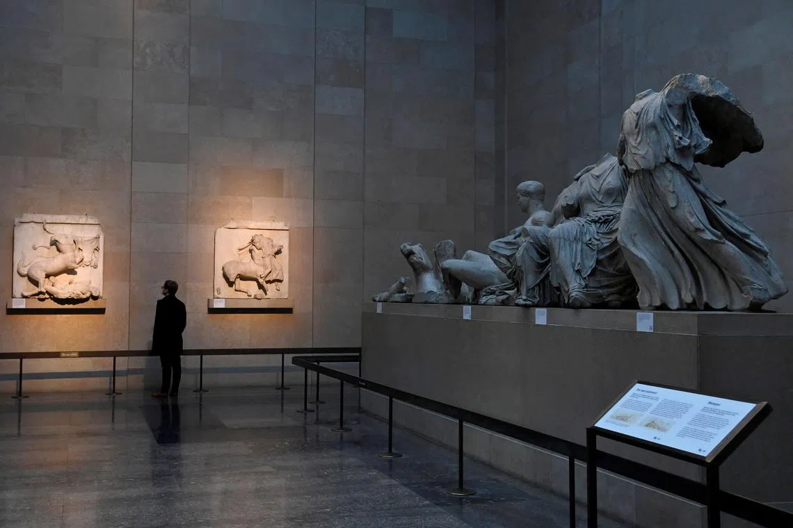 An employee poses as he views Parthenon sculptures, sometimes referred to in Britain as the Elgin Marbles, at the British Museum in London.