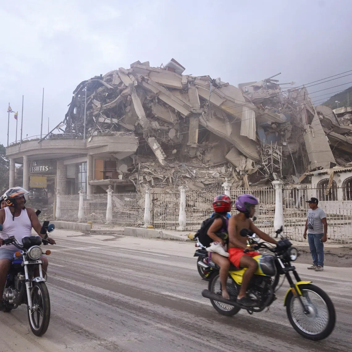 People ride past a collapsed building after an earthquake, in La Guaira, Venezuela, on June 24.
