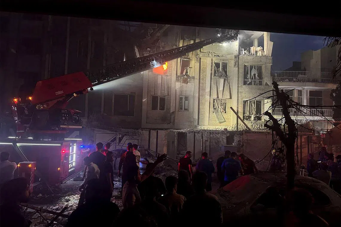 This handout photo released by Iran's Revolutionary Guard Corps (IRGC) official Sepah News Telegram channel on June 13, 2025 shows onlookers and rescue teams in front of a building that caught fire following and Israeli strike on the Iranian capital Tehran early in the morning. Israeli Prime Minister Benjamin Netanyahu said in a video statement in the early hours of June 13 that Israel carried out strikes on Iran and the military operation against the Islamic republic would  "continue for as many days as it takes". (Photo by SEPAH NEWS / AFP) / RESTRICTED TO EDITORIAL USE - MANDATORY CREDIT "AFP PHOTO / SEPAH NEWS  " - NO MARKETING NO ADVERTISING CAMPAIGNS - DISTRIBUTED AS A SERVICE TO CLIENTS