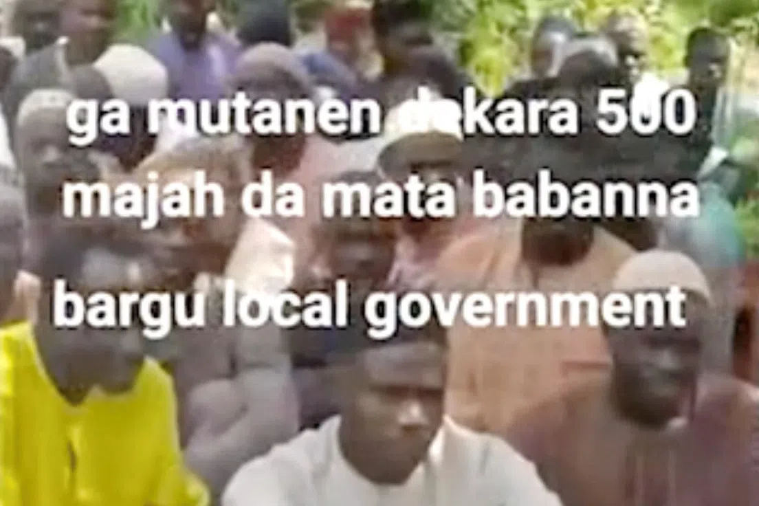 People sit on the grass in this screen grab obtained from a social media video released by an armed group on August 23, 2026, showing what residets said were about 600 women, children and older people abducted in an attack on a mosque in Nigeria’s north-central Niger State. SOCIAL MEDIA/via REUTERS