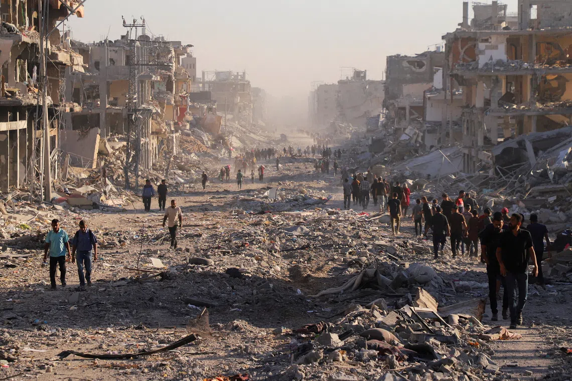 Palestinians walk through a damaged neighborhood in the aftermath of an Israeli operation, after Israel's government ratified a ceasefire with Hamas, in Gaza City, October 10. REUTERS/ Ebrahim Hajjaj