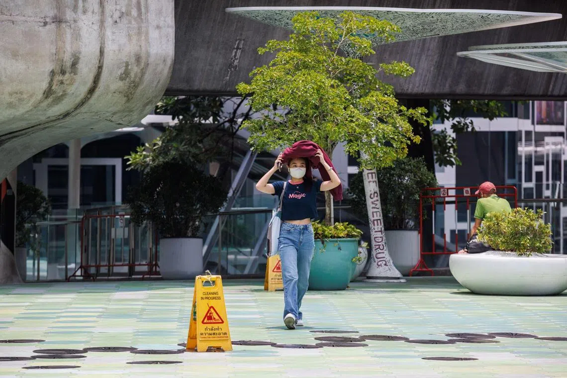 A woman shield herself from the sun during a heat wave in Bangkok, Thailand, on Thursday, April 27, 2023. Thailand’s government will cut power rates ahead of next month’s general election, in an effort to ease the plight of consumers and businesses grappling with sweltering temperatures. Photographer: Andre Malerba/Bloomberg