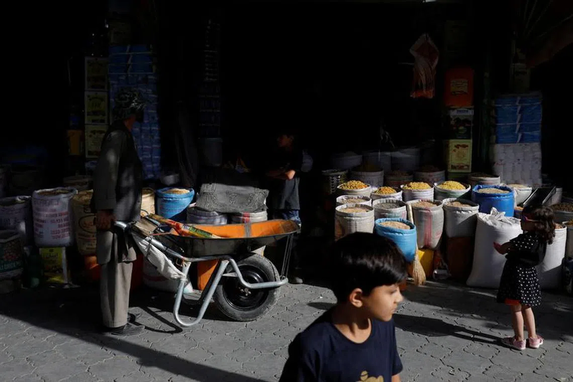 Baba Karim with his wheelbarrow stands next to a shop in Kabul, Afghanistan, September 3, 2023. REUTERS/Ali Khara/File Photo