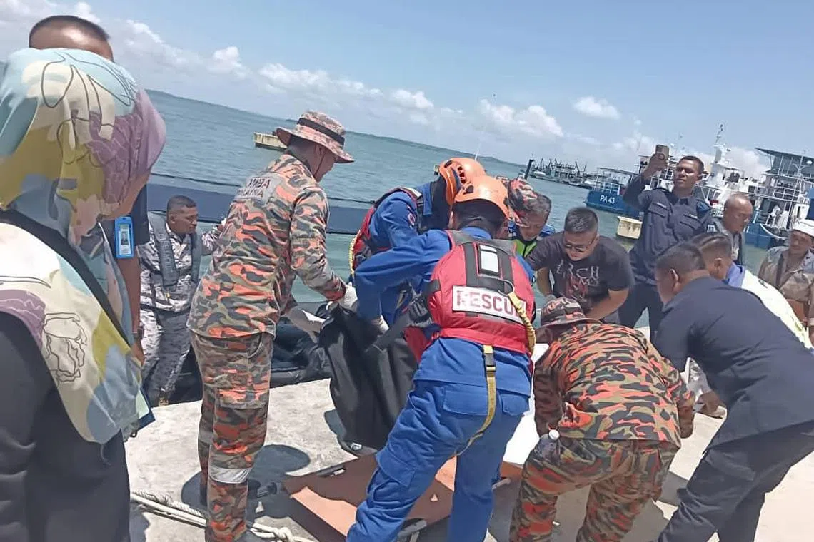 Rescuers wrapping the body of a 12-year-old boy killed by crocodile in Sabah's Sandakan district.