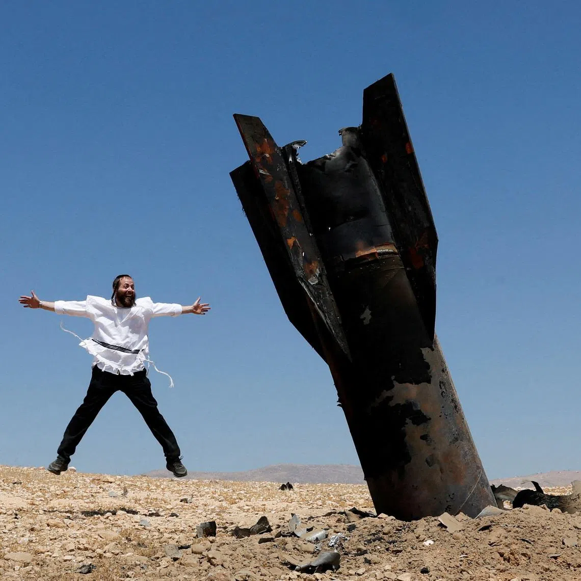 An Israeli ultra-Orthodox Jewish man reacts near a part of a missile protruding from the ground, following strikes from Iran, in the central Israeli-occupied West Bank, June 8, 2026. REUTERS/Ammar Awad