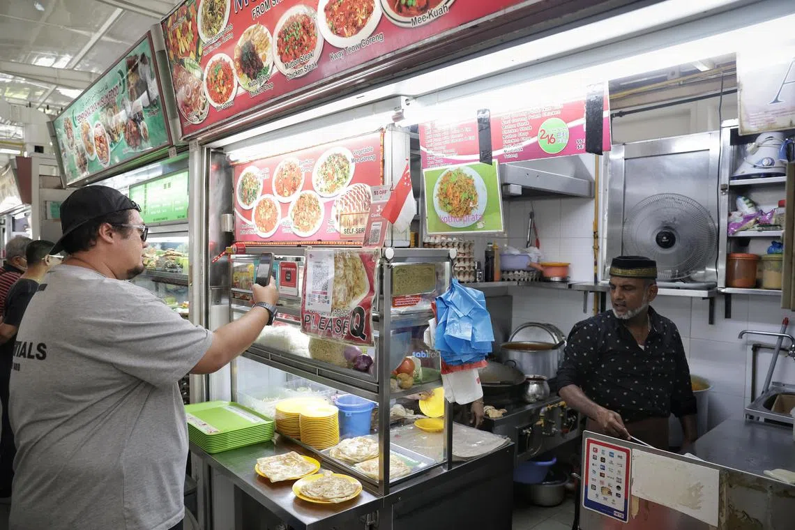 A patron making e-payment at Mohamed Azeem Indian Muslim food stall at Block 216 Bedok Food Centre and Market on Oct 26, 2023. The Government Subsidy for Merchant Discount Rate for Stallholder scheme will be extended  for merchants to digitalise. ST PHOTO: KEVIN LIM ocbedok26
