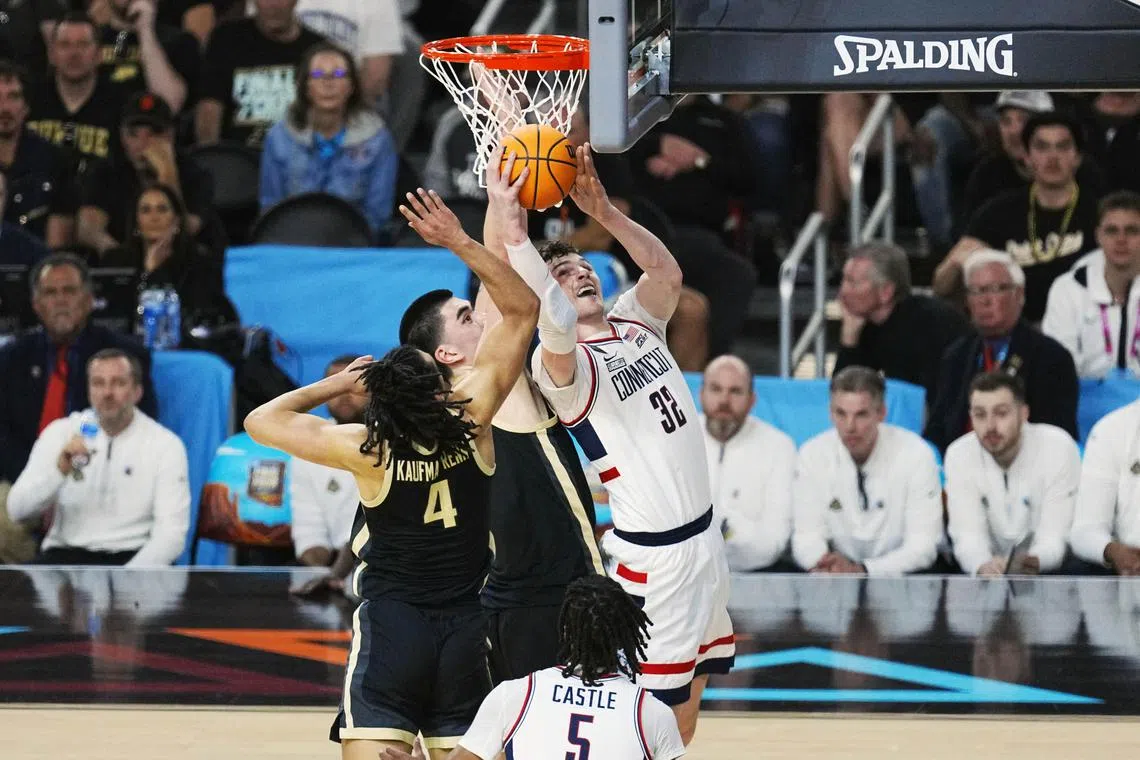 Connecticut Huskies centre Donovan Clingan shoots against Purdue Boilermakers centreZach Edey and forward Trey Kaufman-Renn in the national championship game of the Final Four of the 2024 NCAA Tournament at State Farm Stadium.