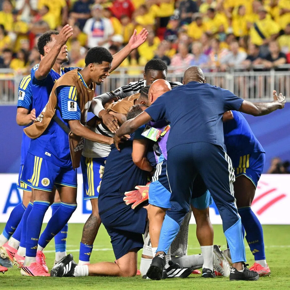 Goalkeeper Eloy Room of Curacao (centre, partially seen) is embraced by some teammates and staff after the 0-0 draw with Ecuador at the World Cup on June 20.