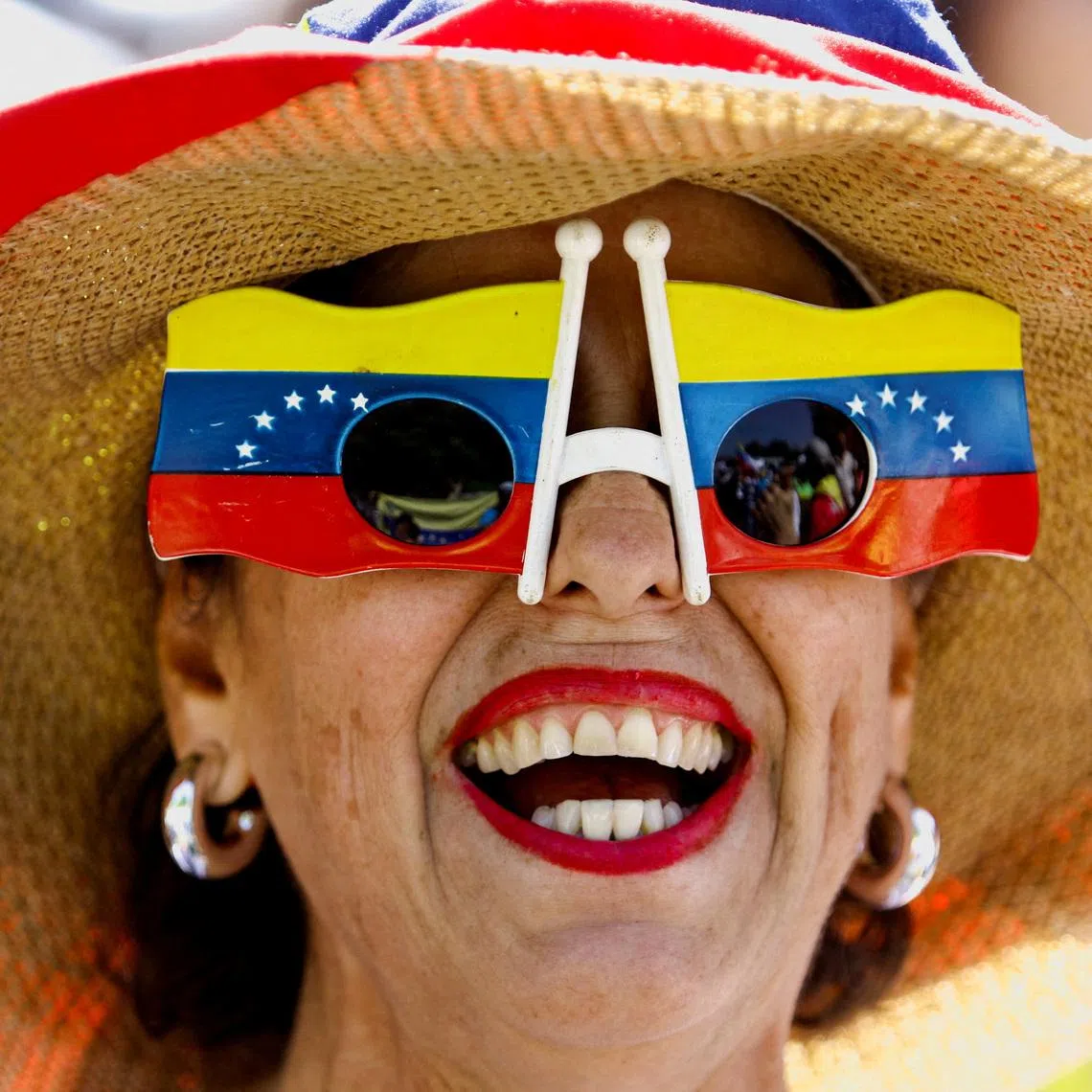 A woman wearing a pair of sunglasses featuring two Venezuelan flags while she takes part in a march calling for amnesty for political prisoners and to mark Youth Day, in Valencia, Venezuela on Febr 12, 2026. 